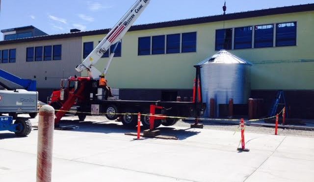Crane lifting equipment near a building with safety cones around.