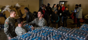 Residents of Flint lined up on Friday to get cases of bottled water distributed by members of the Michigan National Guard. Credit Brittany Greeson for The New York Times